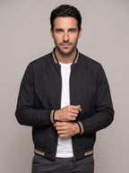 Hombre con chaqueta bomber clásica ÁNGEL IGNACIO en negro, vista en tres cuartos